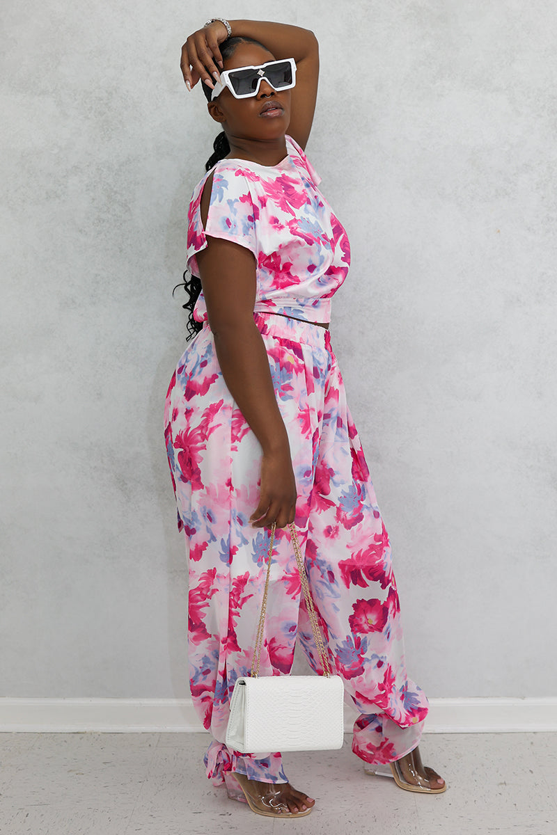 A woman wearing Red Flower Tie Ankle Pants with a vibrant floral design, featuring ankle ties and an elastic waistband for a stylish and comfortable fit.