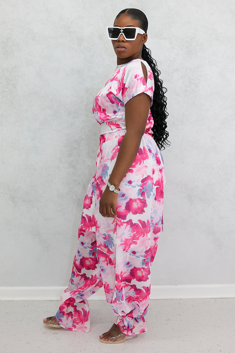 A woman wearing Red Flower Tie Ankle Pants with a vibrant floral design, featuring ankle ties and an elastic waistband for a stylish and comfortable fit.