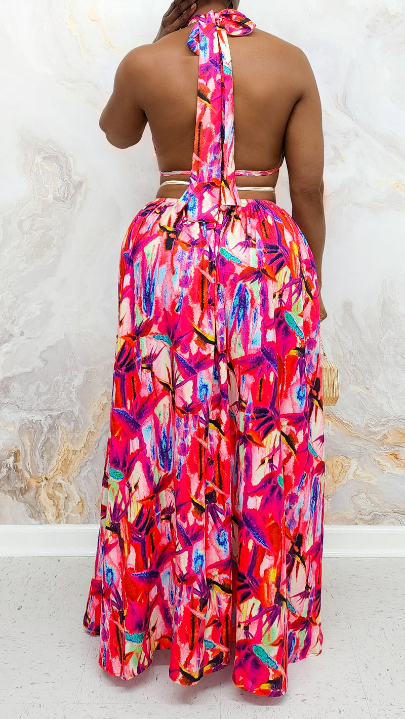 A woman wearing a Resort Island Dress in a vibrant multi-color design, featuring stylish side slits, a silver waistband, and a halter-like tie, made from lightweight silky material for a flattering fit.