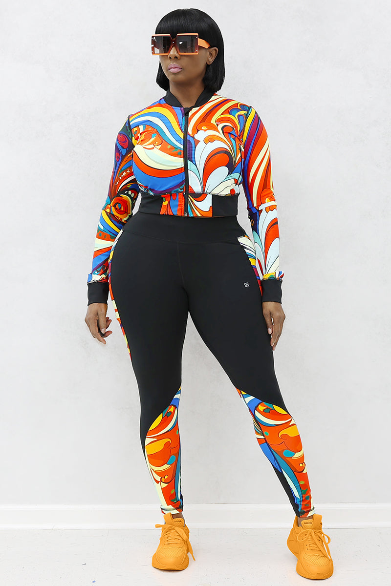 A woman wearing a multi-colored Slit Back Long Sleeve top with vibrant swirl patterns, featuring a snug fit and stylish design ideal for workouts or casual outings.