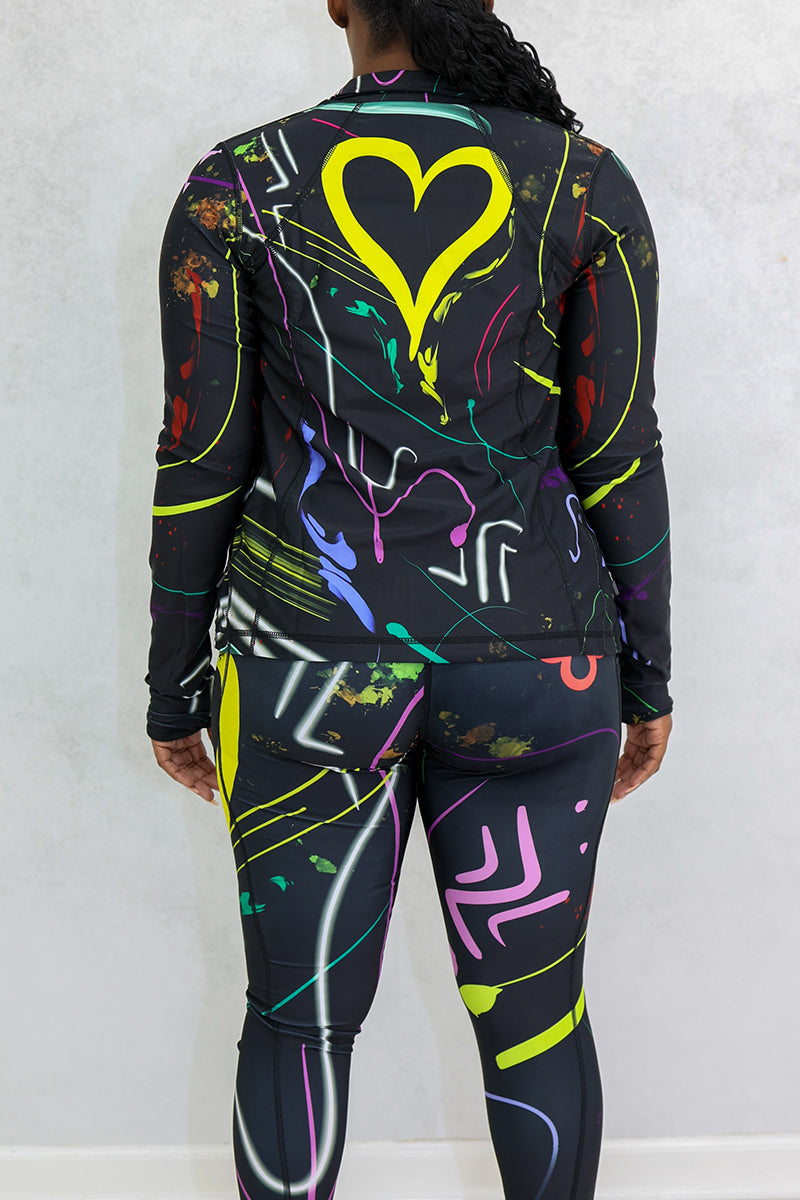 A woman wearing a multi-colored Space Girl Jacket with a glow effect, featuring thumbholes and the Brick-Built logo, perfect for stylish workouts or casual outings.