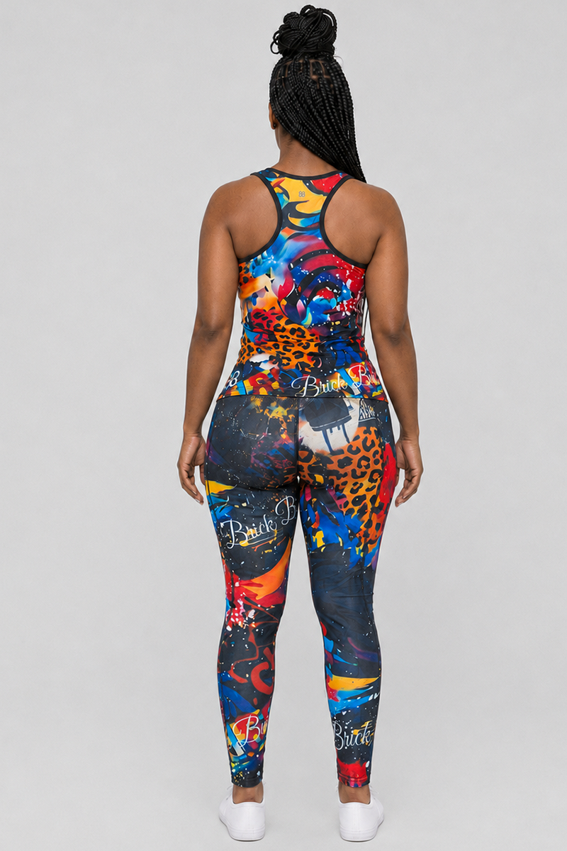 A person stands facing away from the camera, wearing the Art Code Tights—a colorful, patterned athletic outfit with matching leggings and a sleeveless racerback top. The individual's hair is styled in braided updo. Designed with 4-way stretch for ultimate comfort and flexibility, these women's Art Code Tights are perfect for any workout.