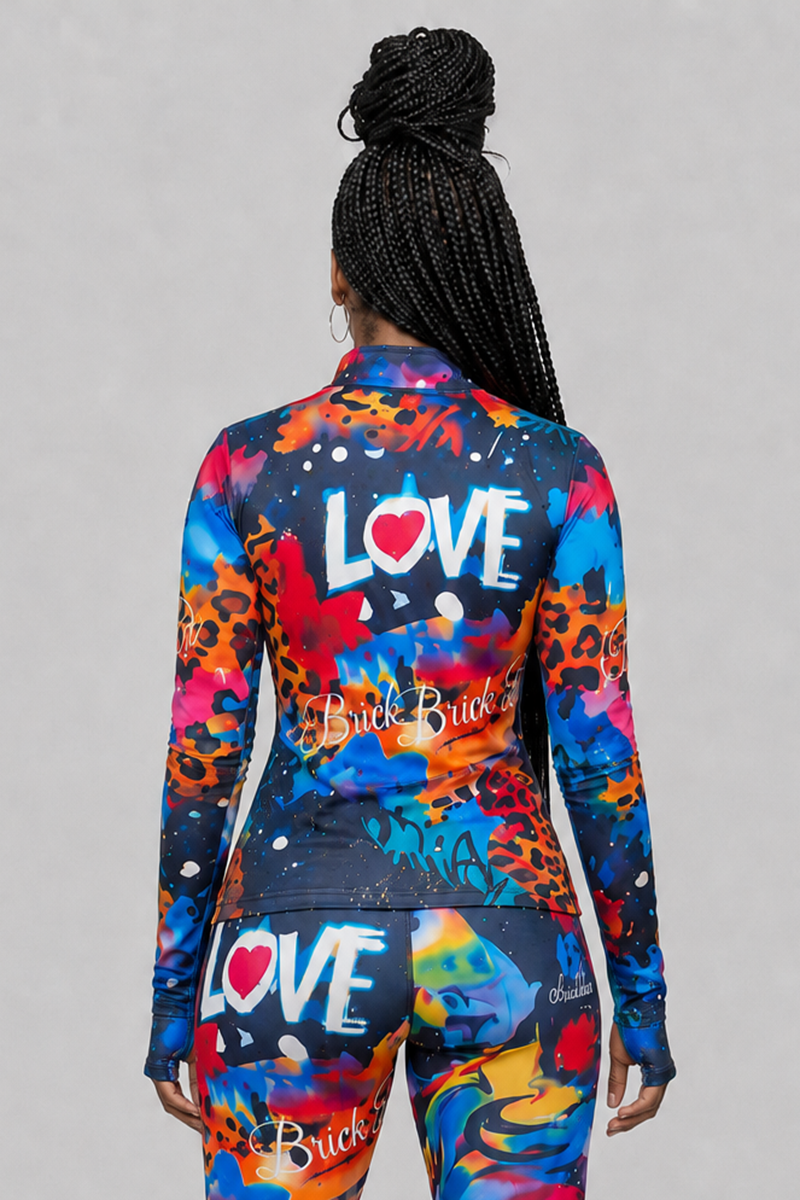 A woman with braided hair faces away, wearing the colorful, form-fitting Art Code Jacket featuring fitted thumbholes and graffiti-style patterns and text—including the word LOVE—on a gray background. Her hands are at her sides.