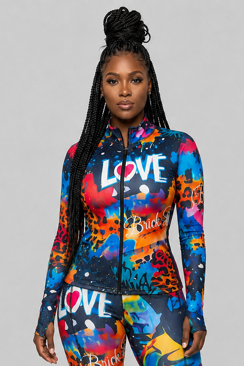 A woman stands facing forward, wearing the Art Code Jacket in multi—a colorful zip-up piece with fitted thumbholes—paired with matching graffiti-print leggings that feature the words LOVE and Brick. She has long braided hair styled in a high bun.