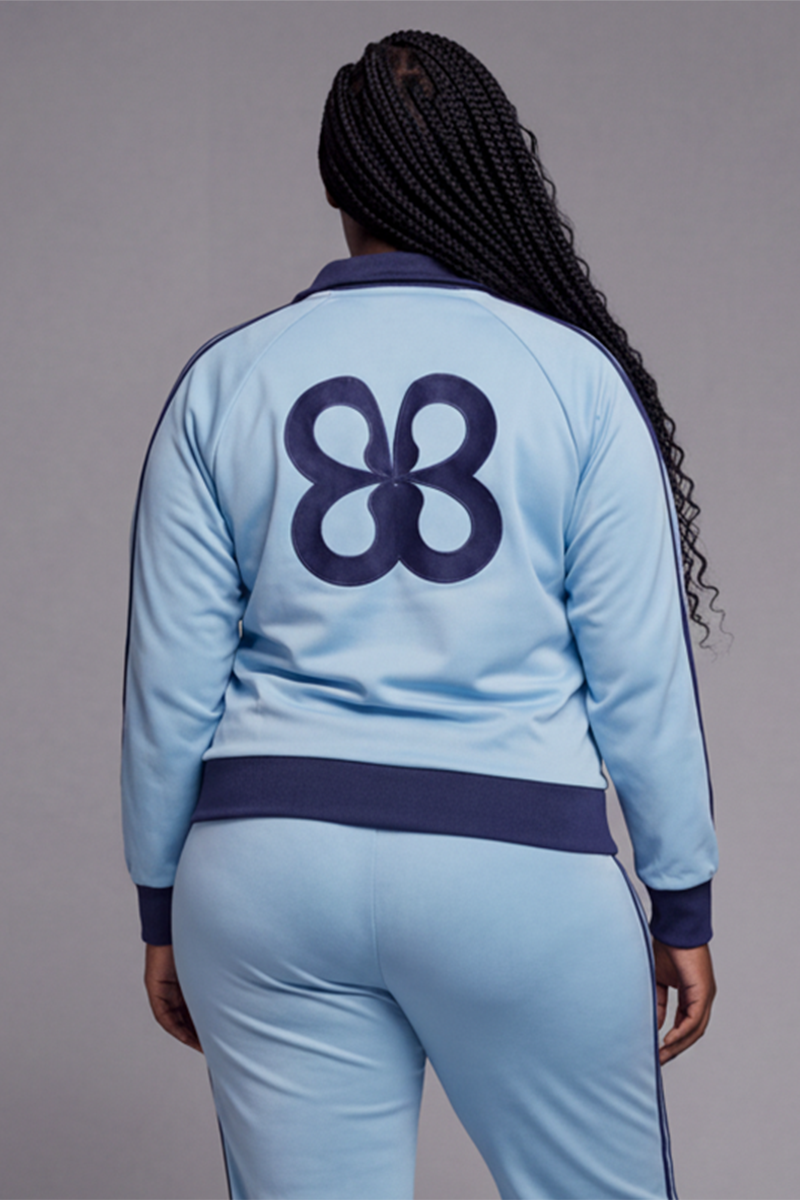 Baby blue track jacket with a navy clover-style graphic on the back.