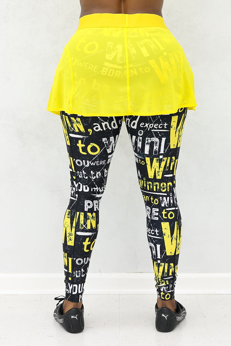 A woman wearing a yellow mesh tennis skirt with printed black tights. The skirt features a stretchy material and a drawstring waist for comfort and style.