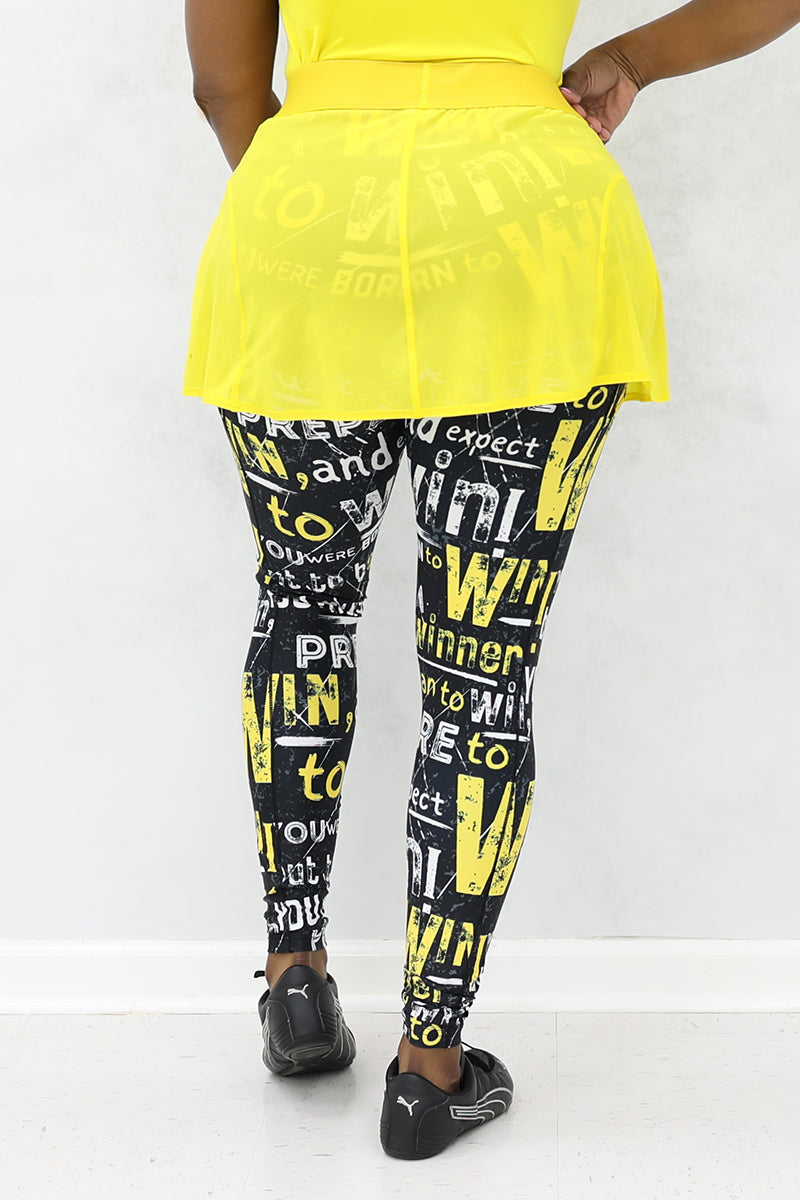 A woman wearing a yellow mesh tennis skirt with printed black tights. The skirt features a stretchy material and a drawstring waist for comfort and style.