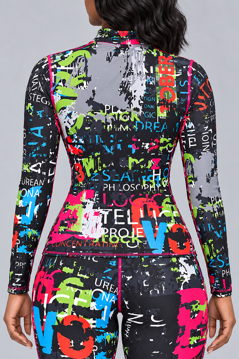 A person stands facing away, wearing the Electric Letters Half-Zip Pullover—a fitted, long-sleeve top crafted from a polyester spandex blend for 4-way stretch—paired with matching pants. The outfit features a colorful, abstract pattern with splashes of green, blue, red, and yellow over a black background scattered with white text, resembling a stylish compression set that offers both comfort and flair.