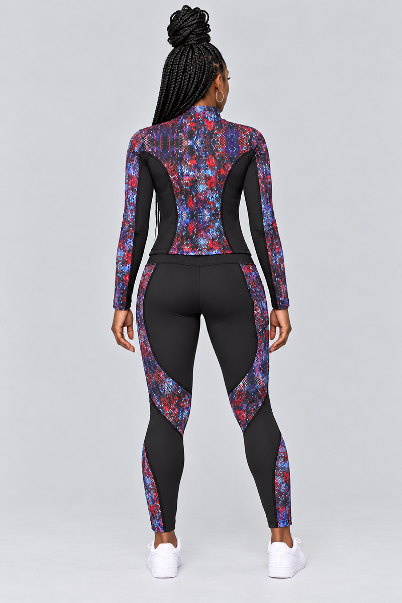 A person with braided hair stands facing away, wearing Kario Tights—a fitted, long-sleeve athletic outfit crafted from polyester spandex with a black base and colorful, flower-like patterns. The body-contouring tights offer a flattering fit, and the ensemble is paired with white sneakers against a light gray background.