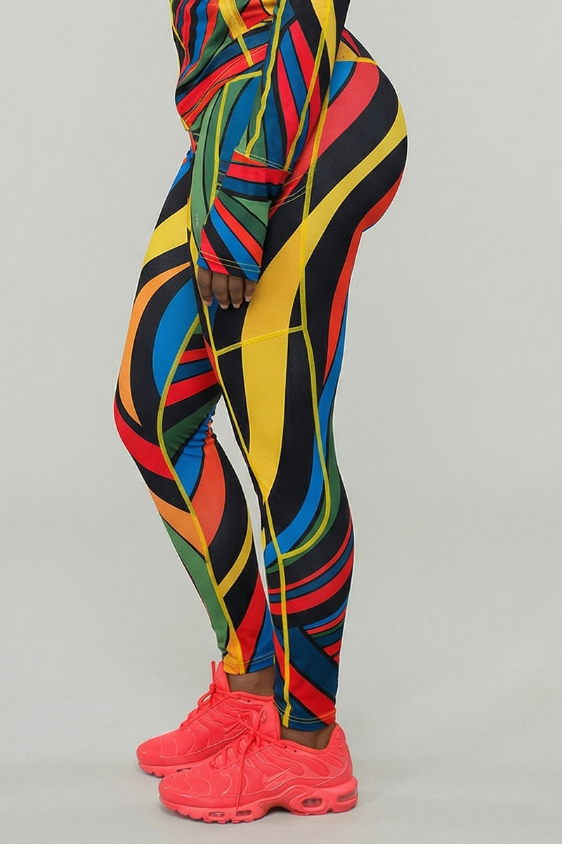 Someone stands in profile against a light gray background wearing Color Riot Tights in Multi, featuring a colorful geometric pattern, with a matching top and bright pink athletic shoes.