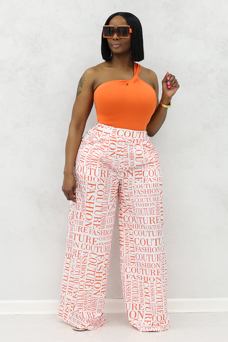 A woman wearing white and orange couture palazzo pants with a stylish design.