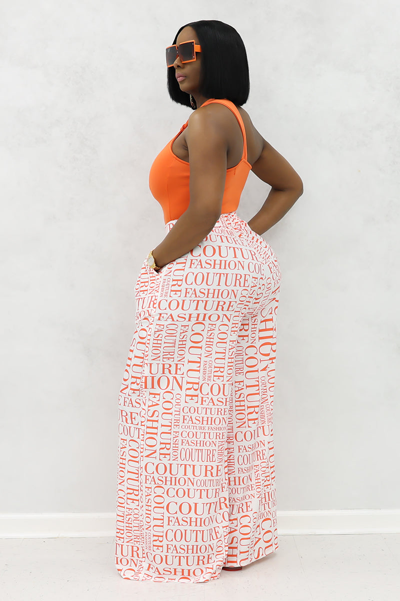 A woman wearing white and orange couture palazzo pants with a stylish design.