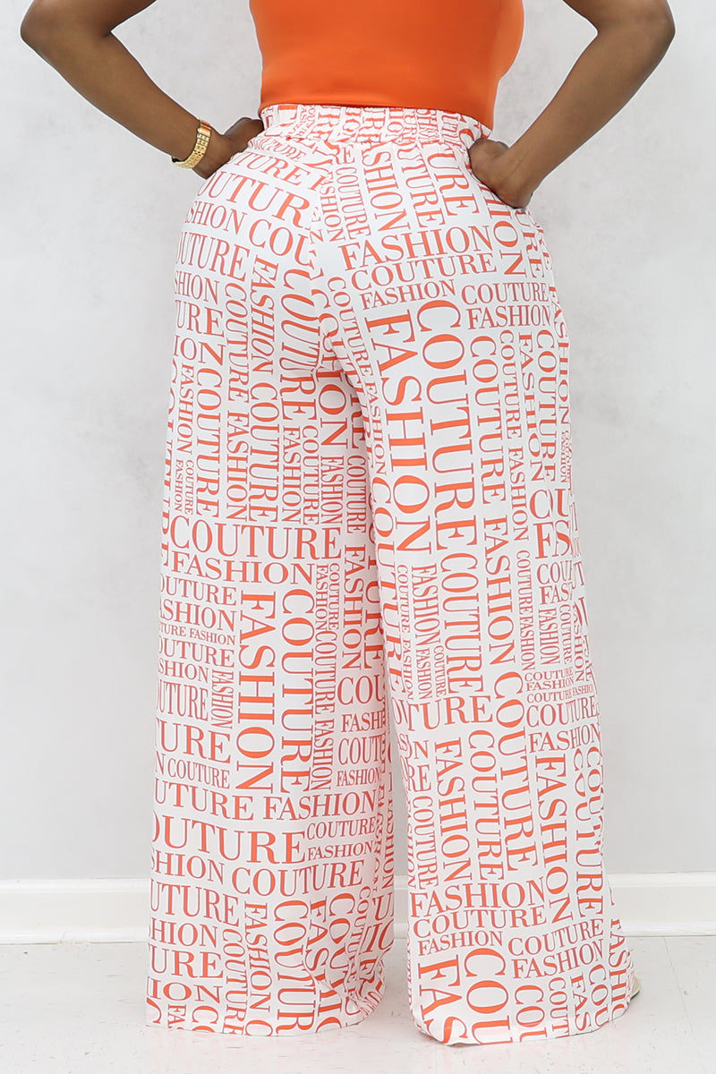 A woman wearing white and orange couture palazzo pants with a stylish design.