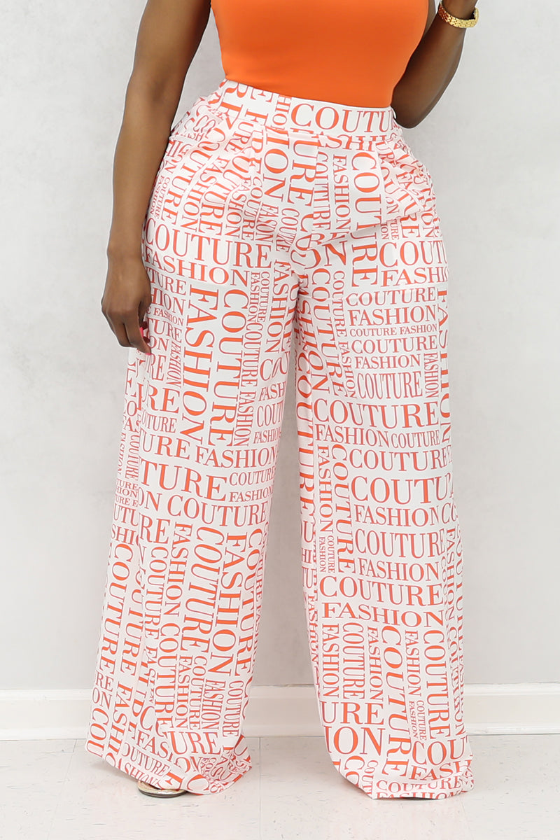 A woman wearing white and orange couture palazzo pants with a stylish design.