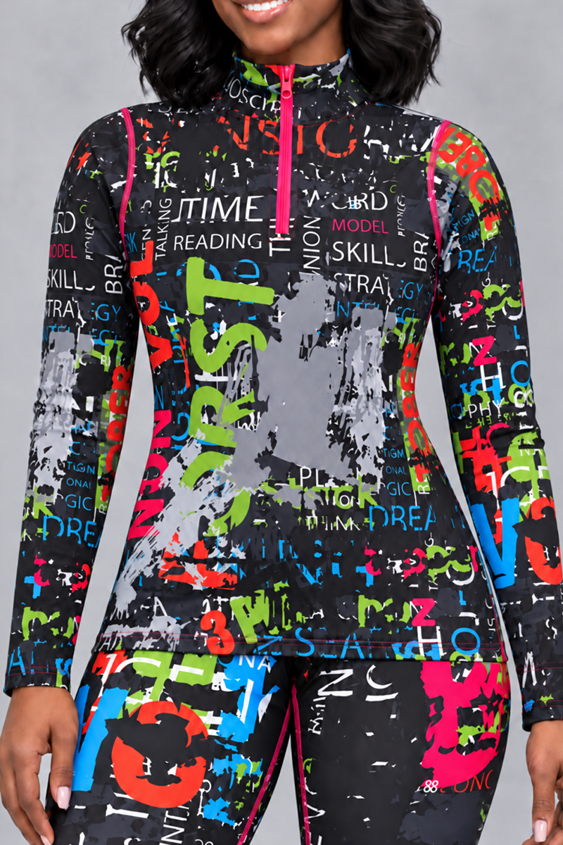 A person wearing the Electric Letters Half-Zip Pullover in Multi, a fitted long-sleeve top made from polyester-spandex with 4-way stretch, featuring a high collar and overlapping multicolored text with paint splatter patterns on a black background; only their lower face and body are visible.