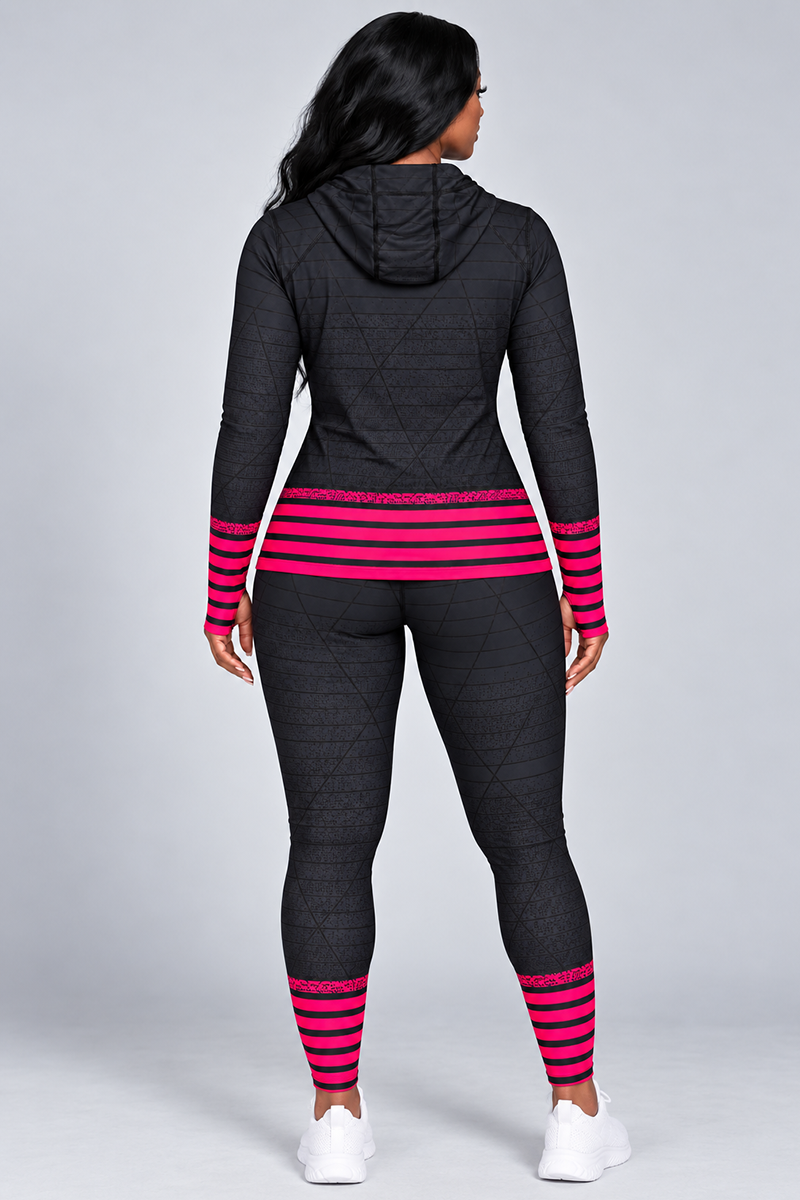 A person stands facing away, wearing the Epic Pullover—a black stretchy hoodie athletic outfit featuring pink and black striped accents on the sleeves and legs. The outfit includes thumbhole sleeves for added comfort, complemented by white sneakers, against a plain light gray background.