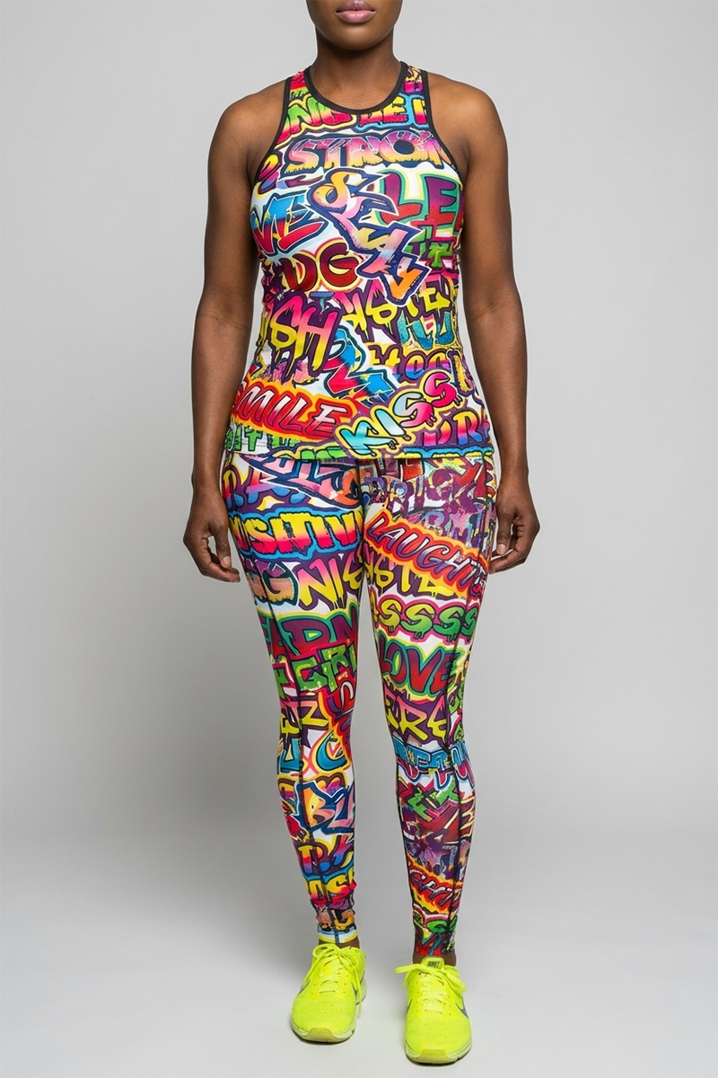A person stands facing forward in the Graffiti Tank Top and matching leggings, both with a colorful graffiti print on moisture-wicking polyester spandex. Neon yellow sneakers complete the outfit against a plain light gray background.