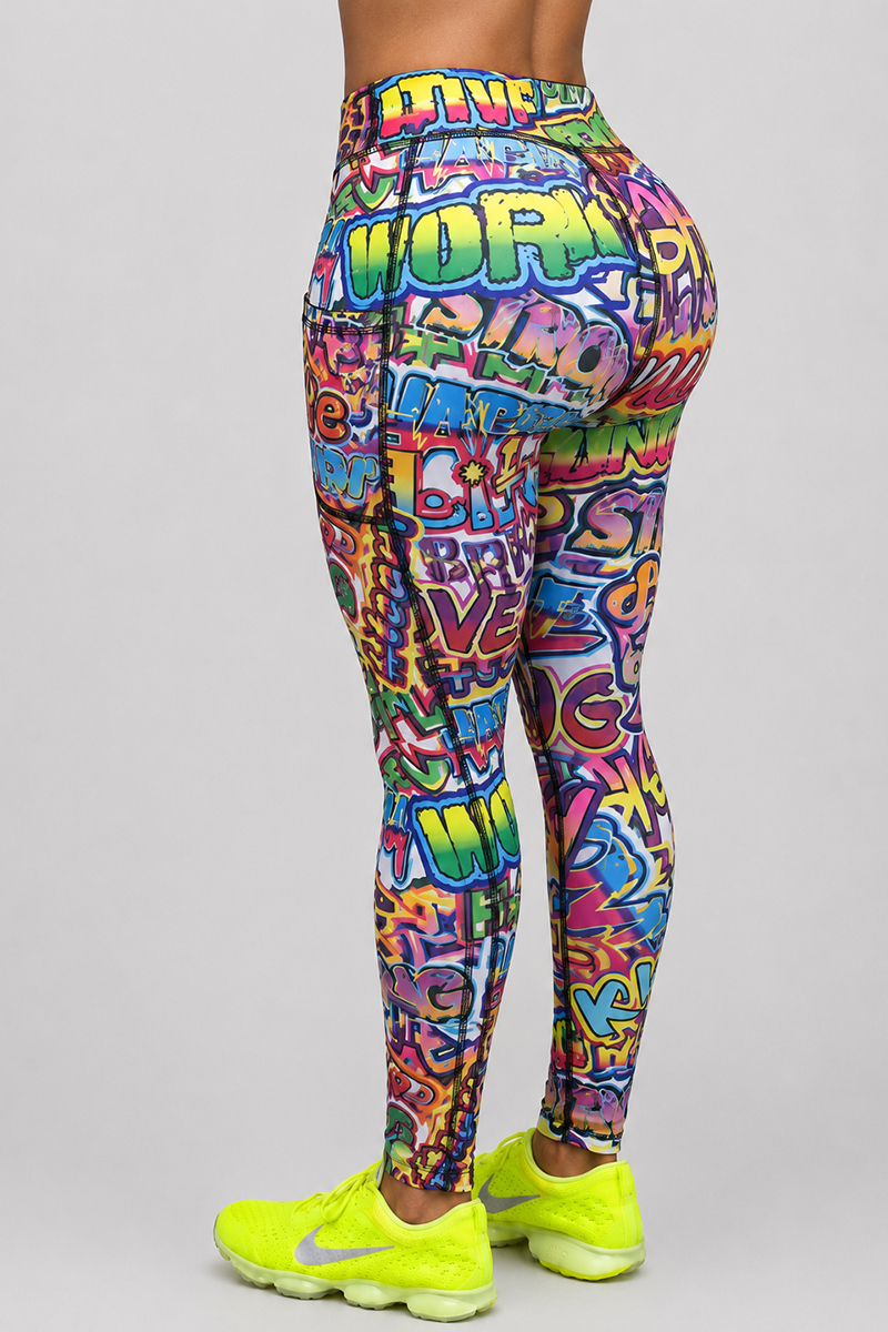 Wearing Graffiti Tights, a person stands facing away. The vibrant gym tights feature a bold graffiti design, paired with neon yellow athletic shoes. The background is plain light gray.
