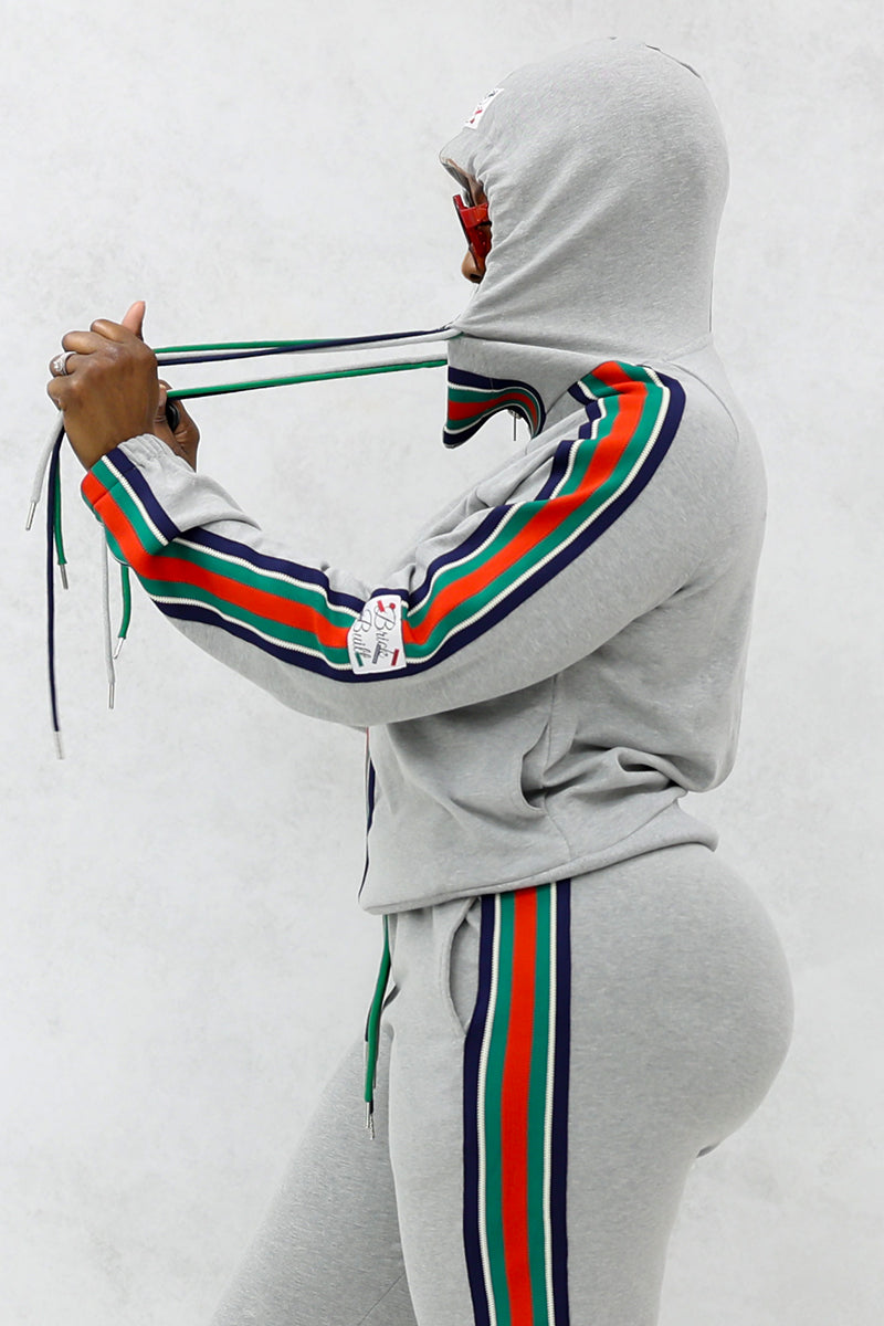 Woman wearing a gray font stripe hooded jacket with multi-colored shoulder stripes