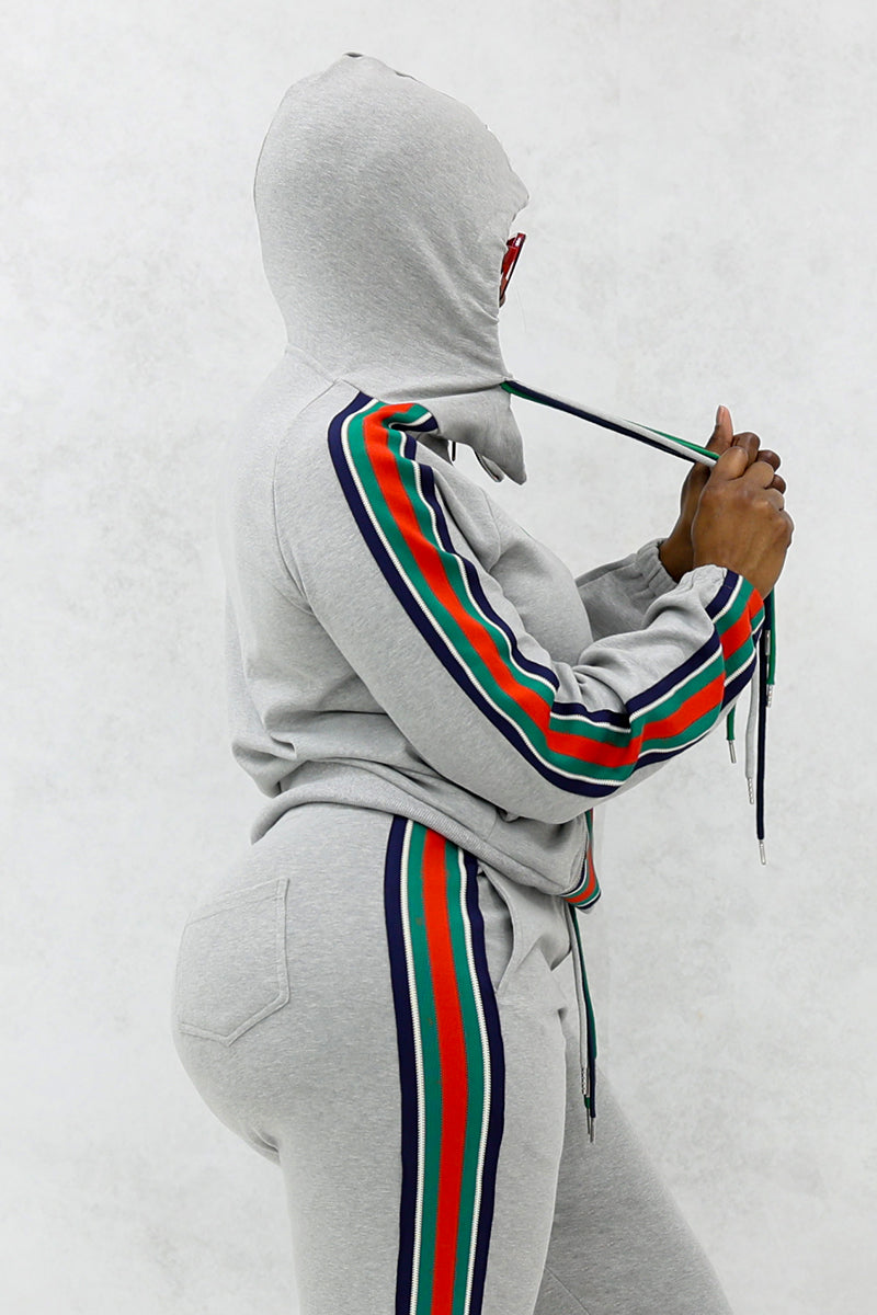 Woman wearing a gray font stripe hooded jacket with multi-colored shoulder stripes