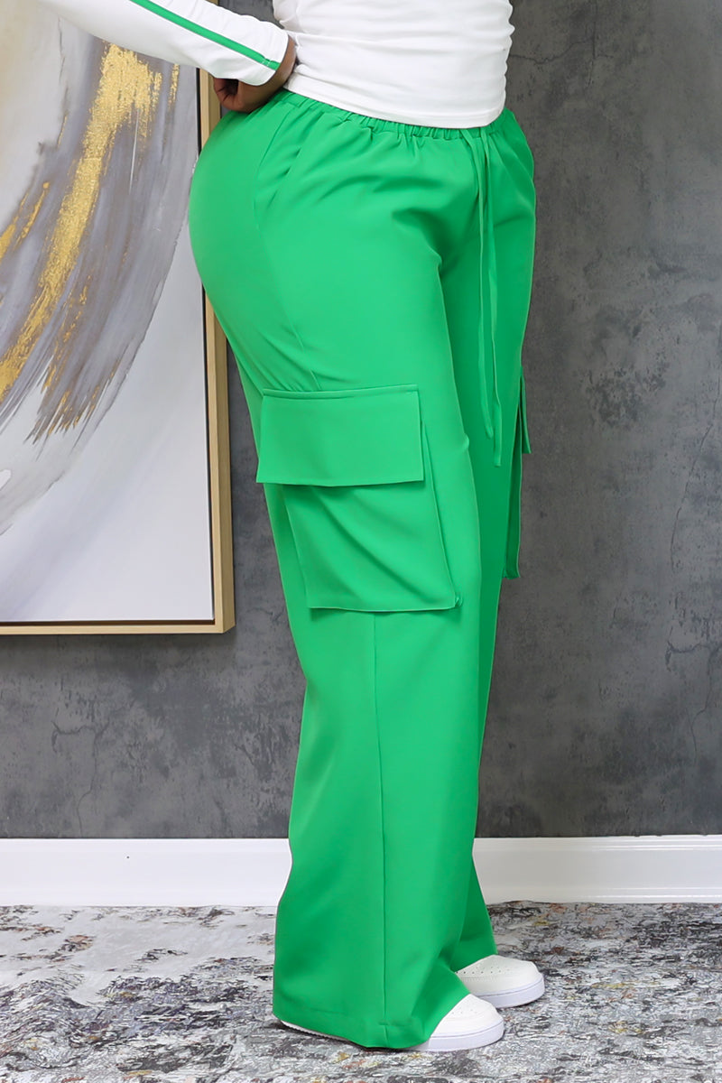 A woman wearing green cargo pants featuring large pockets, an elastic waistband, and a comfortable, flexible fit.