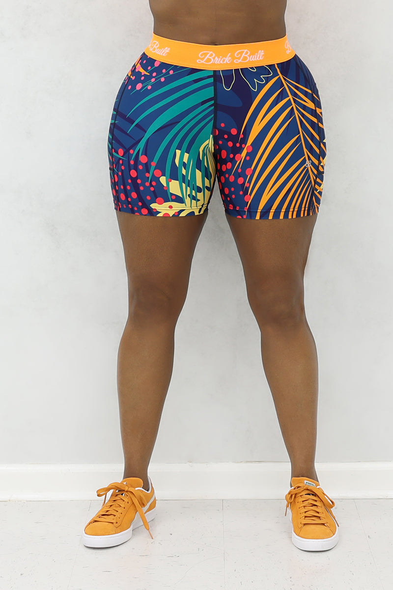 A woman wearing multi-colored Hawaii shorts made of stretchy polyester and spandex, featuring a side pocket.