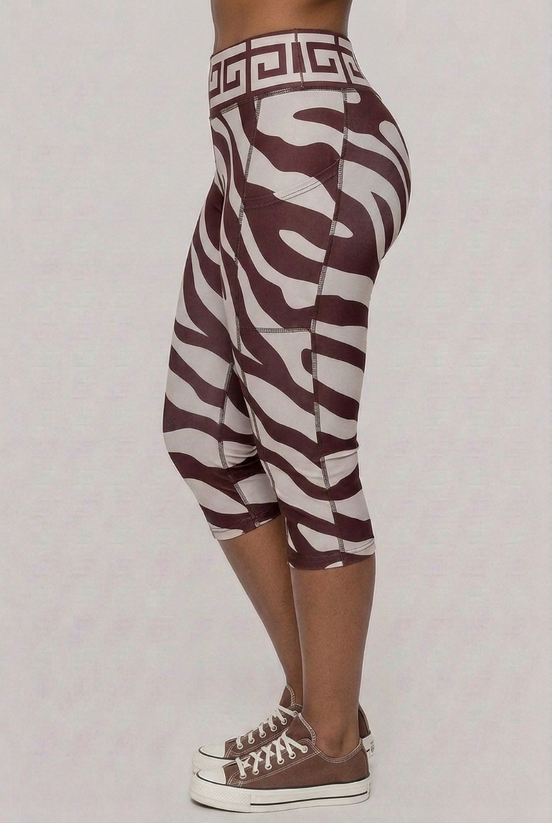 A side profile view of the maroon zebra-print capri leggings, showing the high-waisted fit and the athletic seam detailing along the leg.