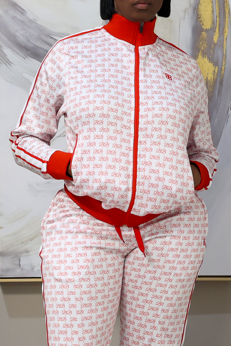 Wearing the BB Monogram Jacket—white with red stand collar, repeating red logo pattern, red trim, and zipper—a person stands hands-in-pockets against an abstract background, their face partially out of frame.