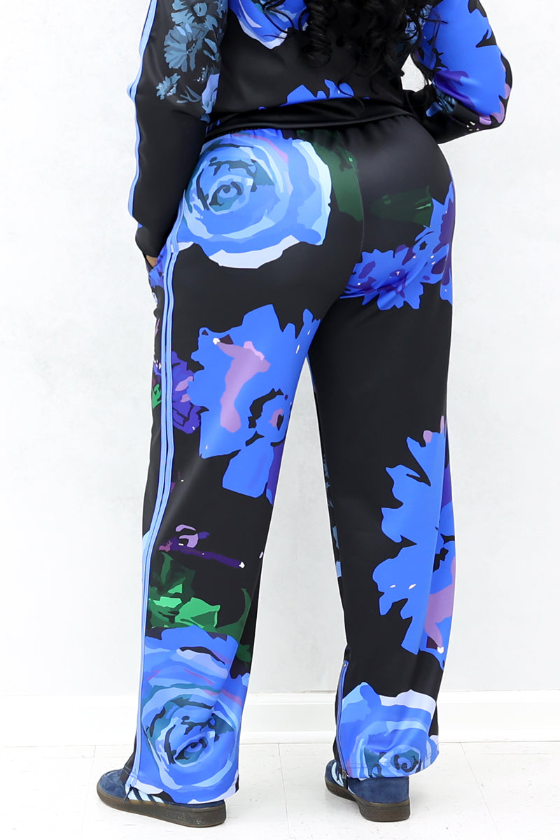 Black pants with blue roses are shown from the back. The pants are loose. 