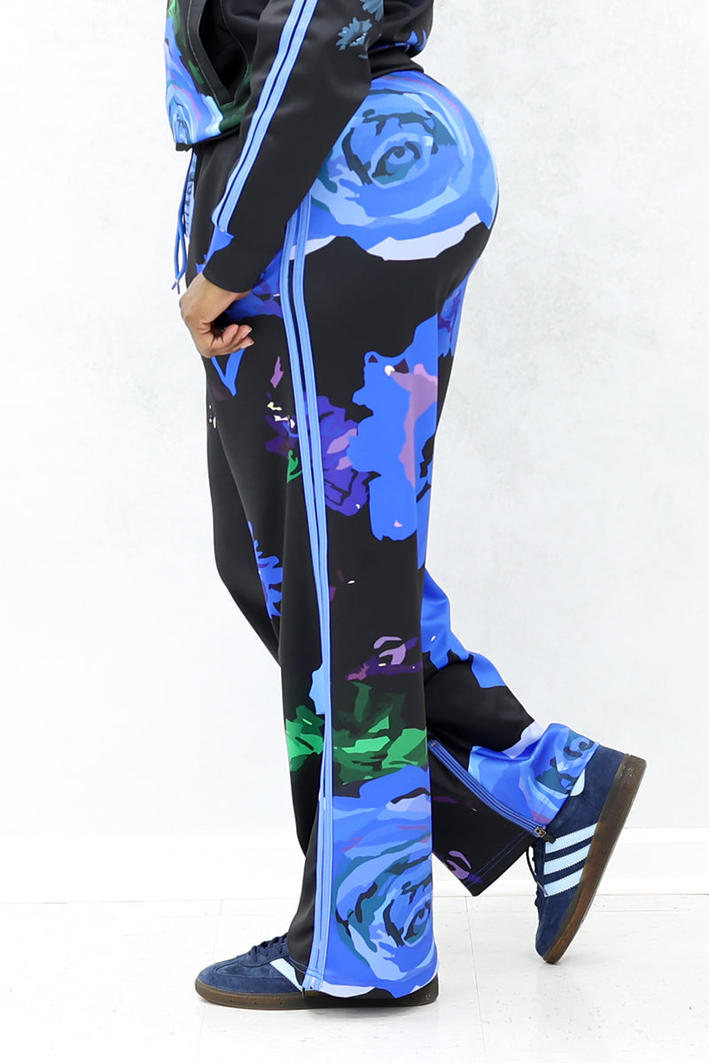 A side-angle view of the black pants with blue roses. The black pants with blue roses have a relaxed fit.