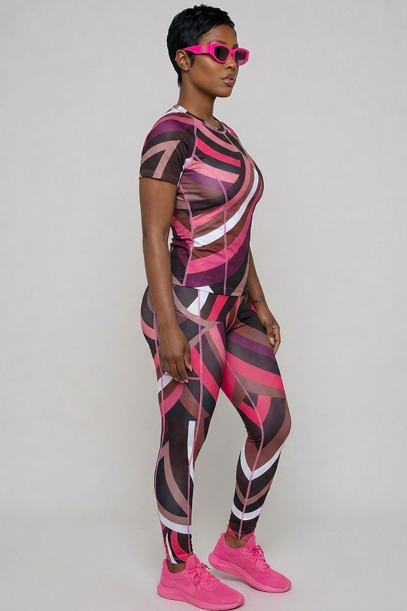A person faces right against a plain background, wearing Sable Tights with a geometric pink, black, and white pattern, paired with pink athletic shoes and pink sunglasses.