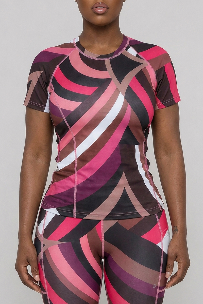 A person stands against a plain background wearing the Sable Tshirt in Multi, featuring a geometric pattern. The short-sleeve athletic top is made from stretchy, lightweight, and breathable fabric for all-day comfort.