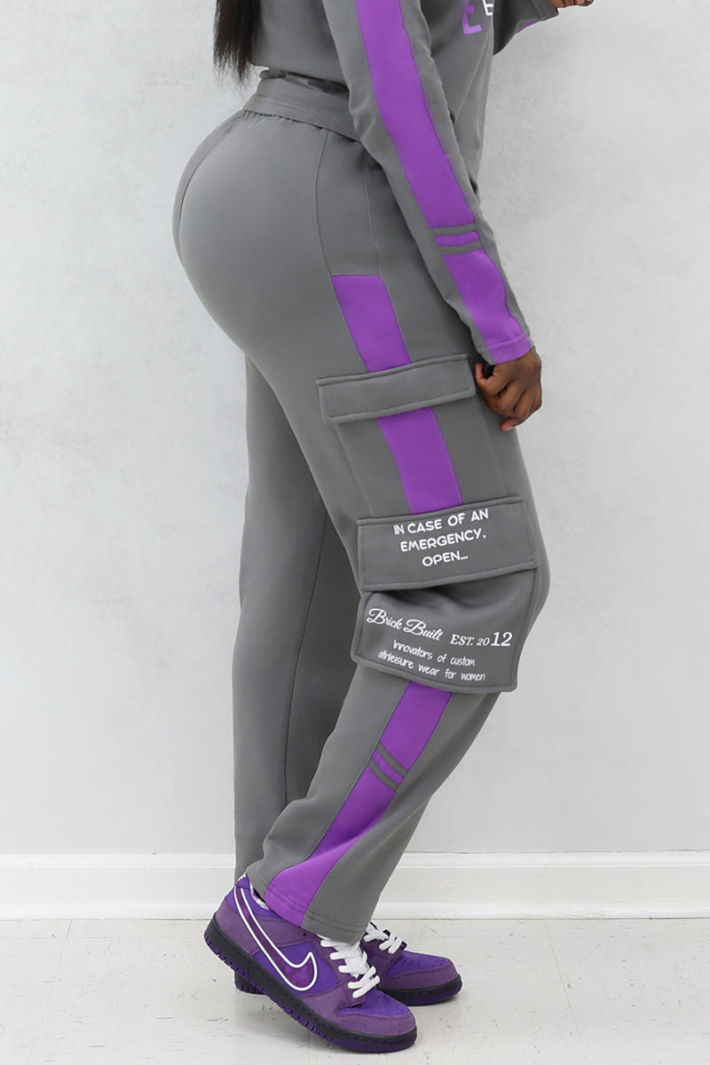 A woman wearing gray and purple cargo joggers with pockets and purple Nike shoes