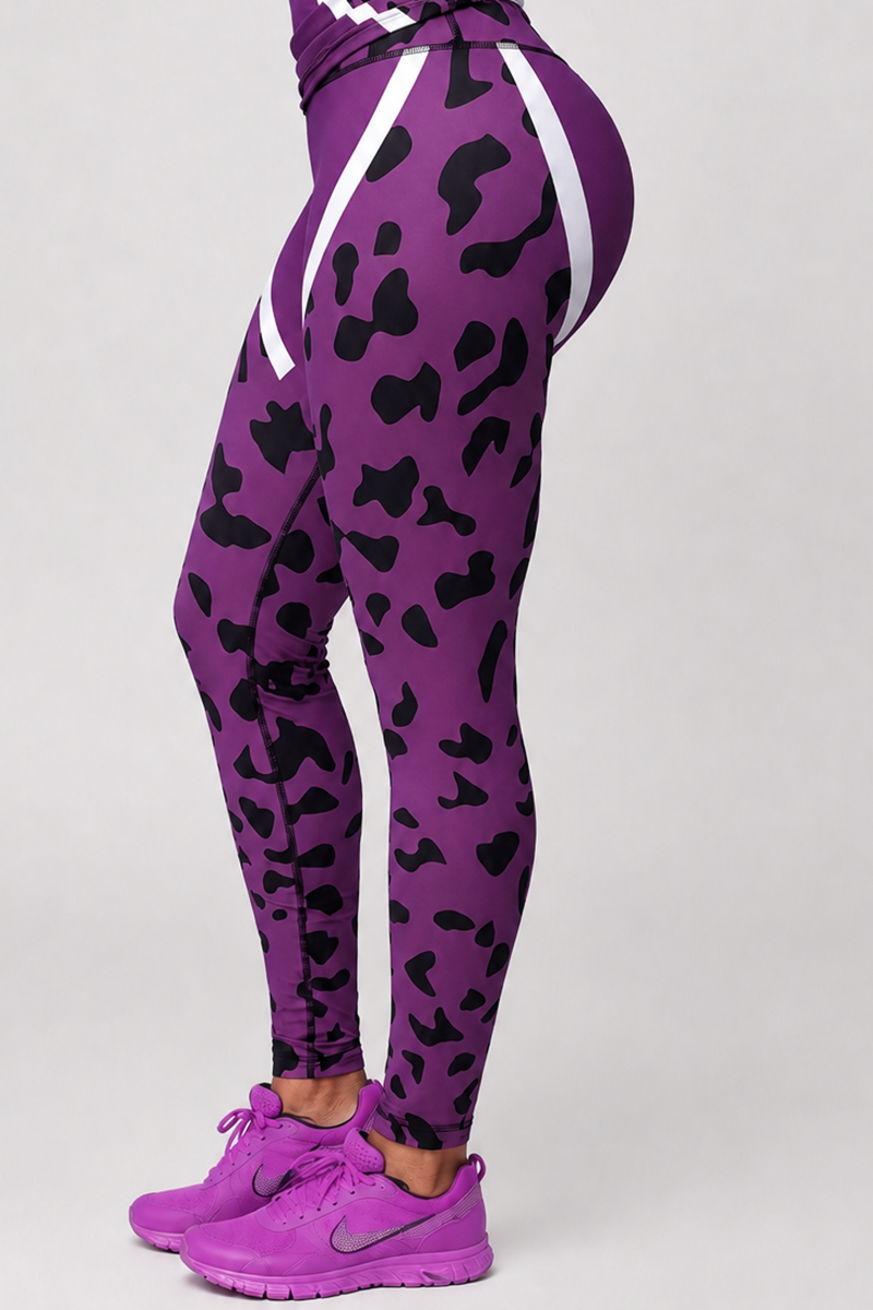 A person is wearing Purple Leopard Tights, featuring a black abstract print and white diagonal stripes, made from moisture-wicking polyester spandex for a body-contouring fit, paired with purple Nike sneakers. Only the lower body and legs are visible in the image as they stand on a light-colored surface.