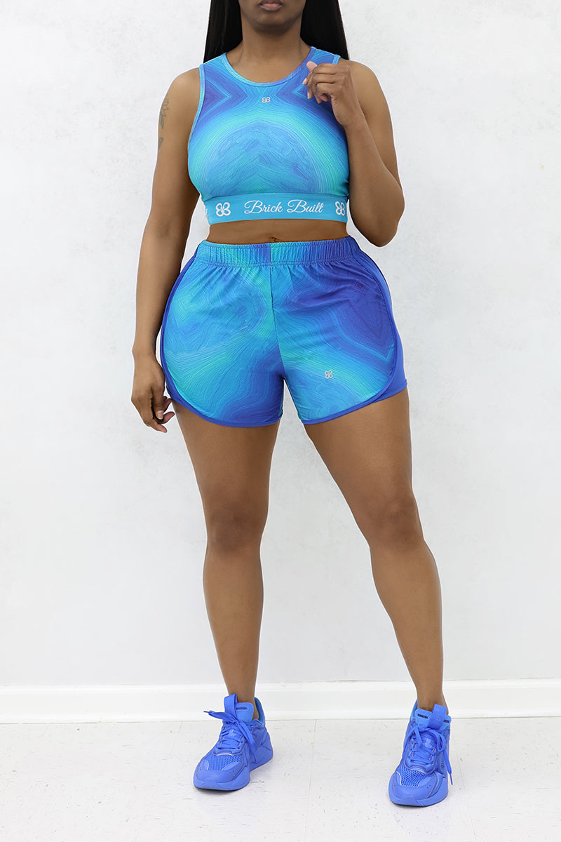 A woman wearing blue Spiral Training Shorts designed for performance and style, featuring a stretchy fit for maximum comfort during workouts or casual wear.