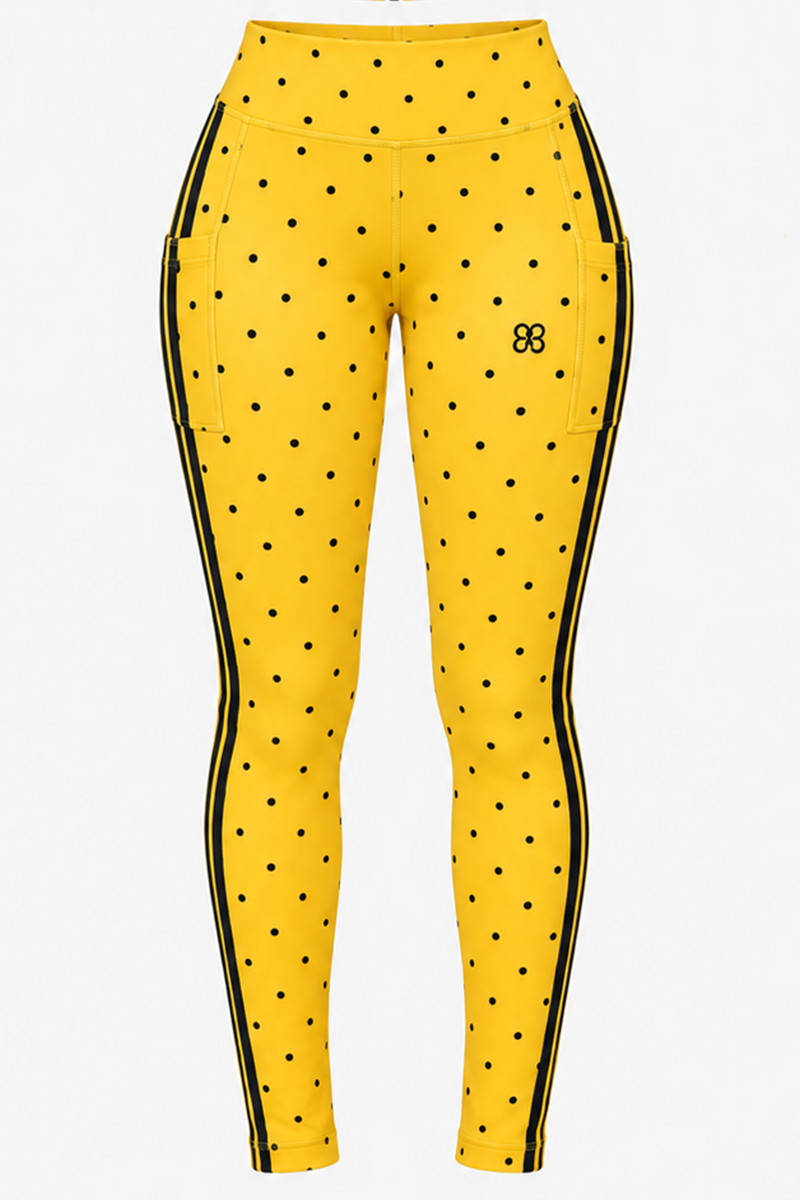 Spotlight Tights (SAMPLE SALE) in Yellow-Black feature a high-waisted design with black polka dots, side pockets, black vertical stripes along the outer sides, and a small black logo on the left hip. Displayed on a plain white background, these discounted activewear leggings are part of Brick Built’s collection.