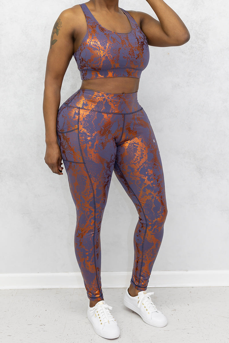 A stylish woman wearing a copper Foil Reptile sports bra with a sleek design.