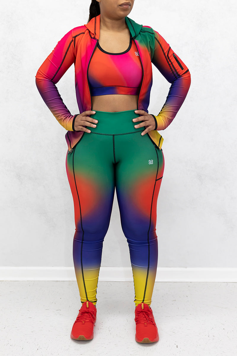 A beautiful woman wearing a multi-colored Gradient Flow jacket featuring a stylish gradient pattern and a hood for added warmth.