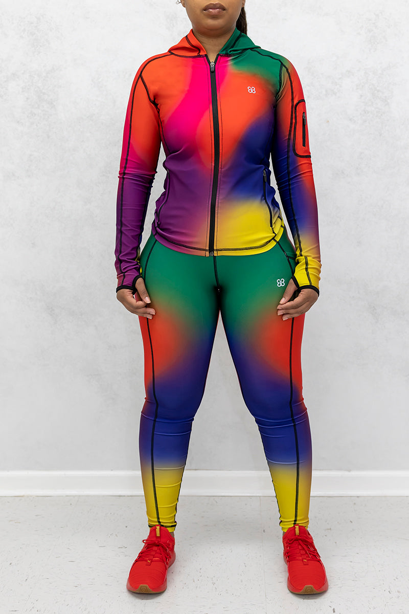 A beautiful woman wearing a multi-colored Gradient Flow jacket featuring a stylish gradient pattern and a hood for added warmth.