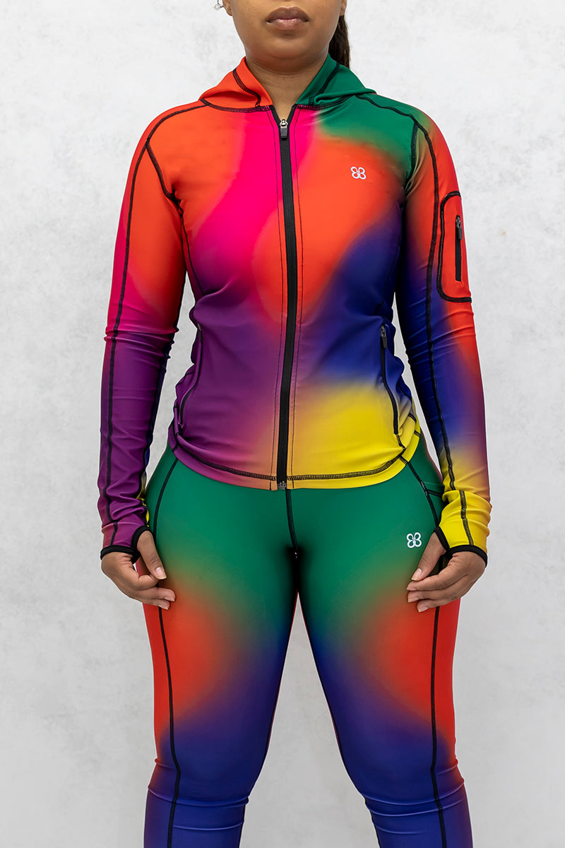 A beautiful woman wearing a multi-colored Gradient Flow jacket featuring a stylish gradient pattern and a hood for added warmth.