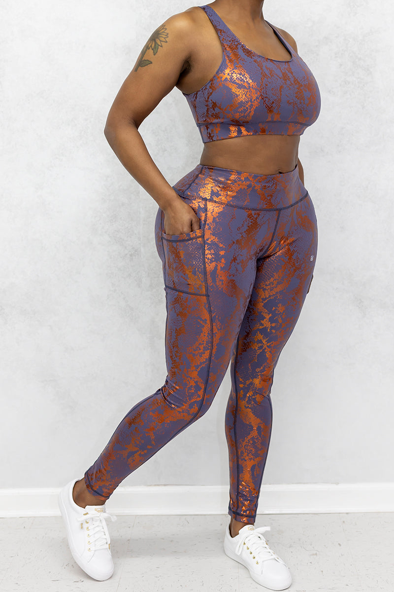 A stylish woman wearing a copper Foil Reptile sports bra with a sleek design.